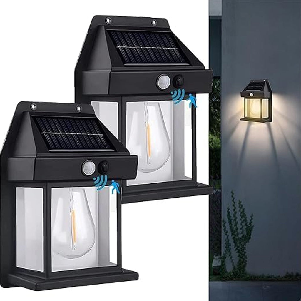Two black solar wall lamps with clear bulbs are shown, one illuminating a wall in the background at dusk.