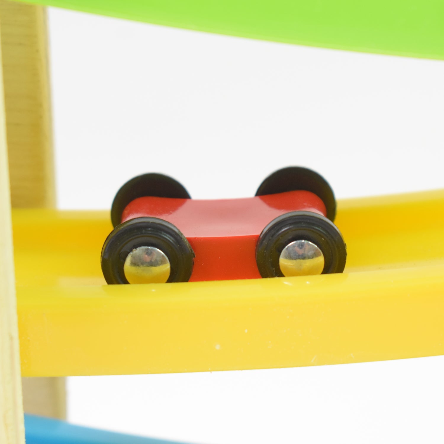 Child's hand placing a mini car on the top level of the wooden race track toy.