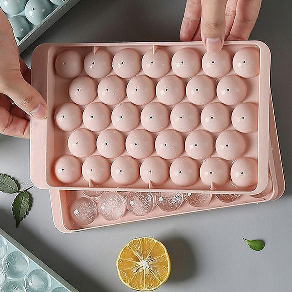 The ice ball mold alongside a glass of chilled beverage, ready for serving.