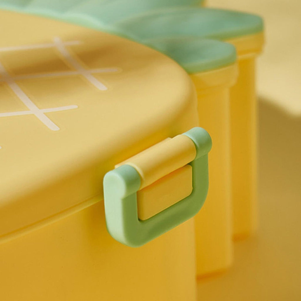 Child's hand opening the vibrant pineapple bento lunch box to reveal compartments.