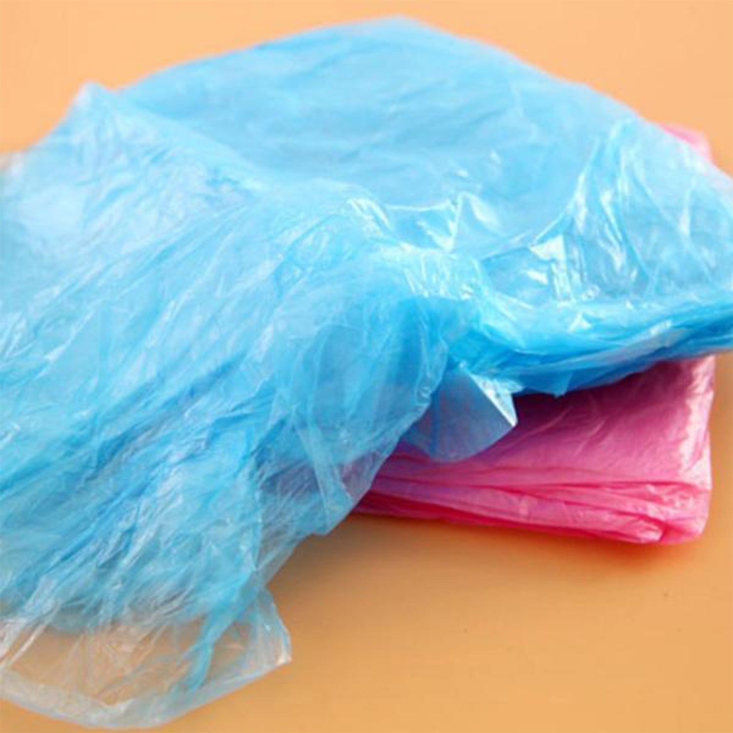 A close-up shows crumpled blue and pink translucent plastic material, likely disposable ponchos, on a flat surface.