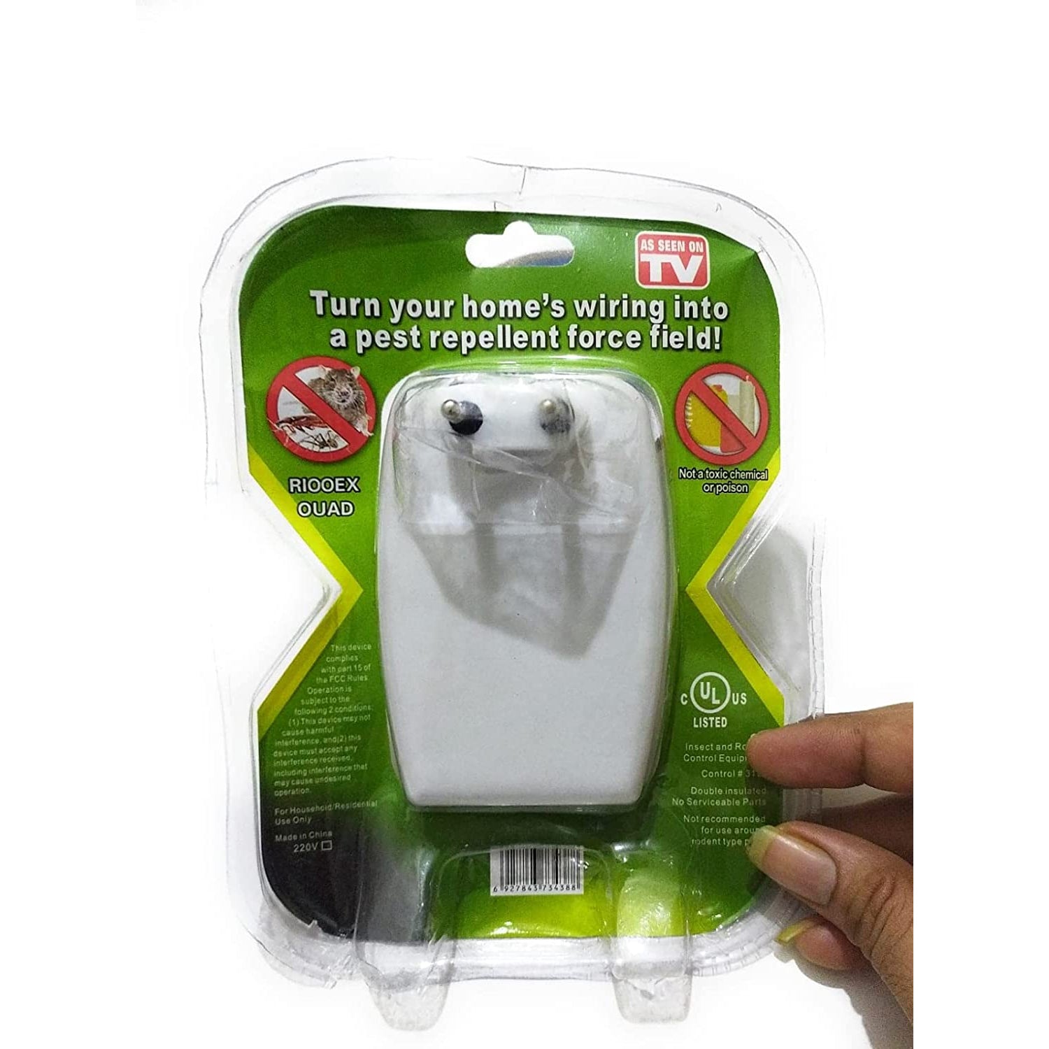 A hand holding a clear plastic package containing a white pest repeller with two metal prongs visible.