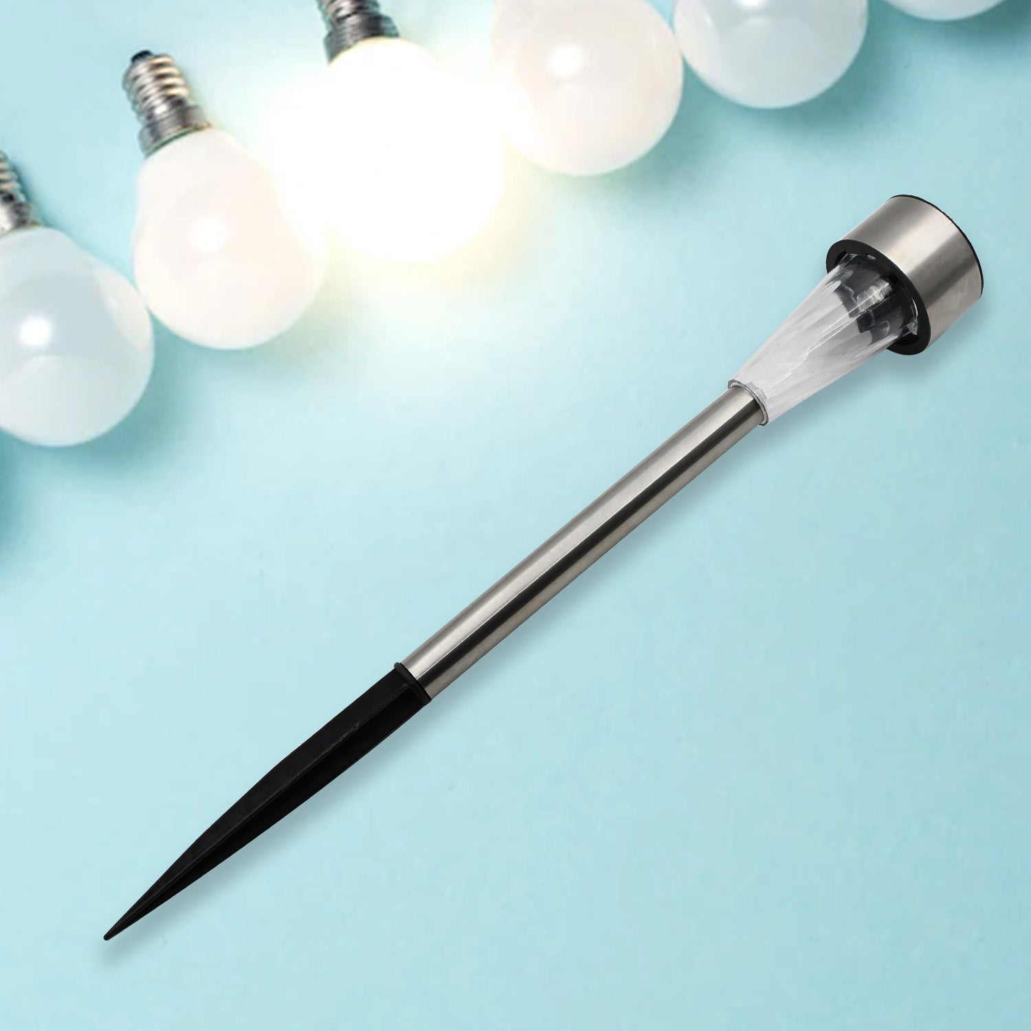 A silver solar LED spike light with a black ground stake is displayed on a light blue background with glowing bulbs.