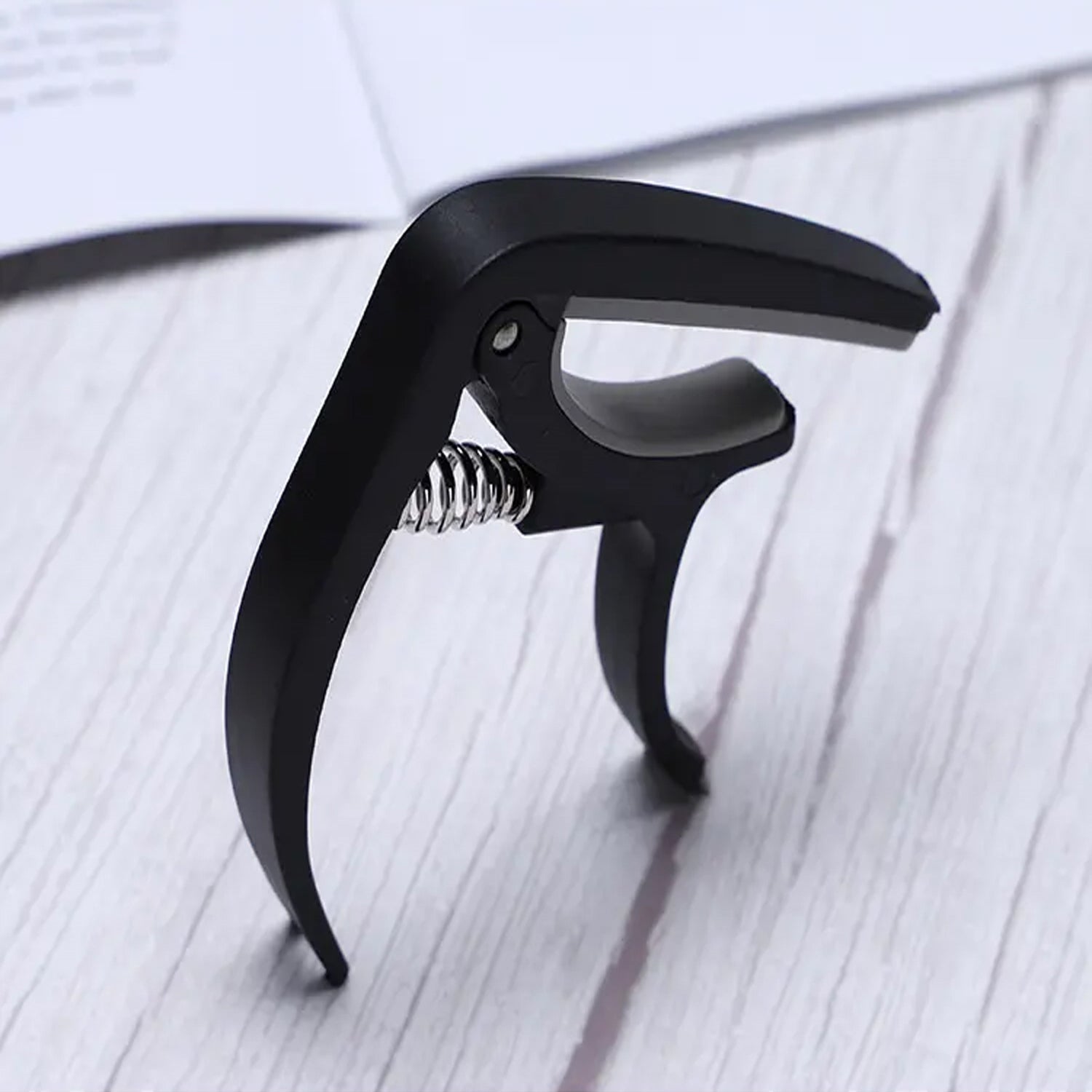 Guitar capo and pick holder positioned on a guitar neck, ready for playing.