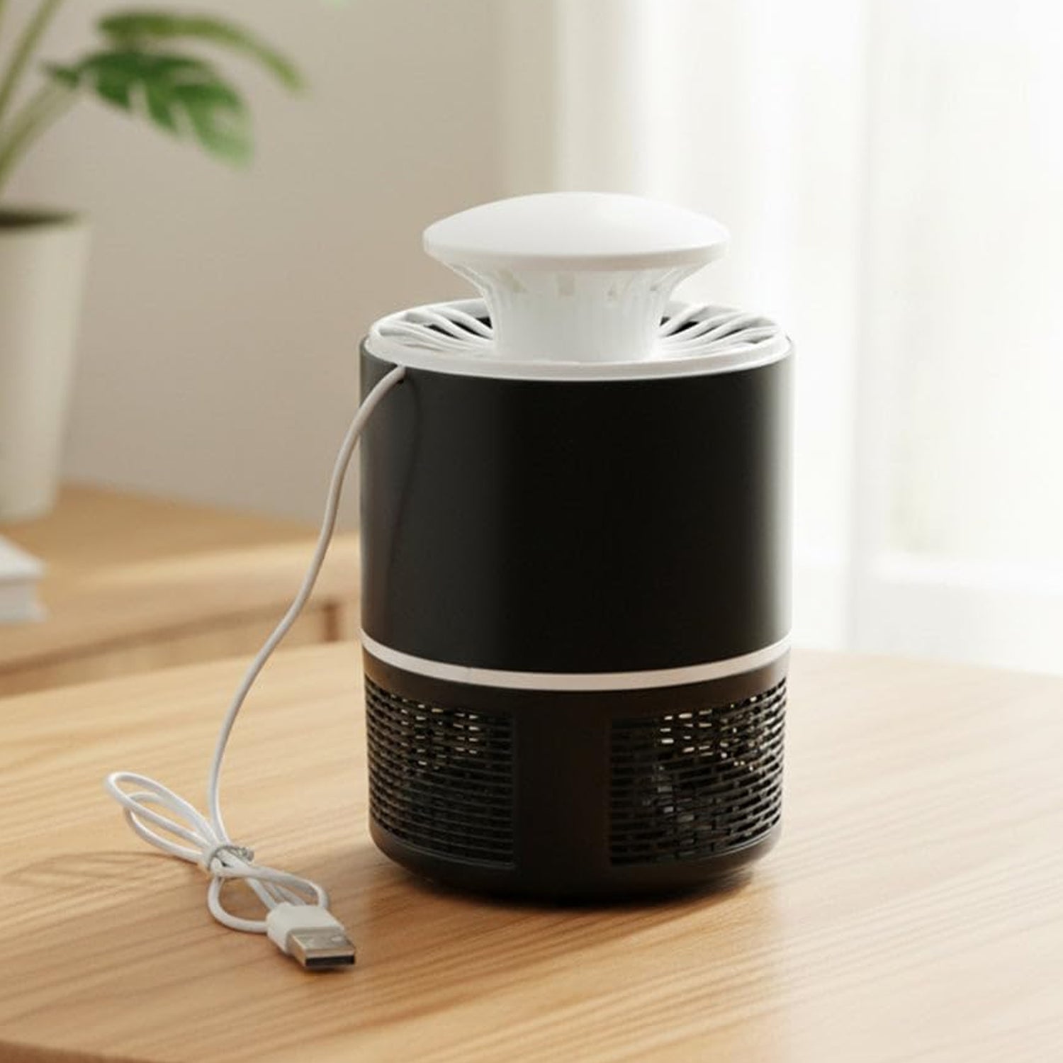 A black and white Mosquito Killer Lamp with a white USB cable on a light brown wooden table.