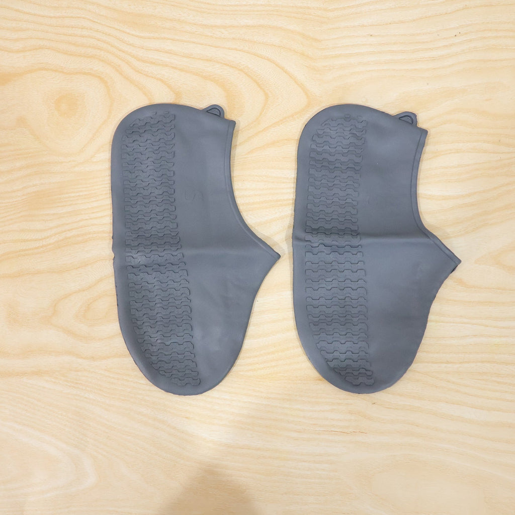 Two gray silicone foot protectors with textured soles are neatly arranged on a light wooden surface.
