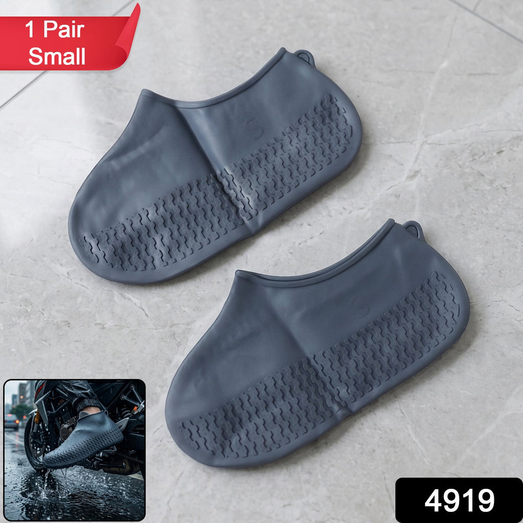 A pair of gray silicone foot coverings with textured soles on a tiled floor, with a red